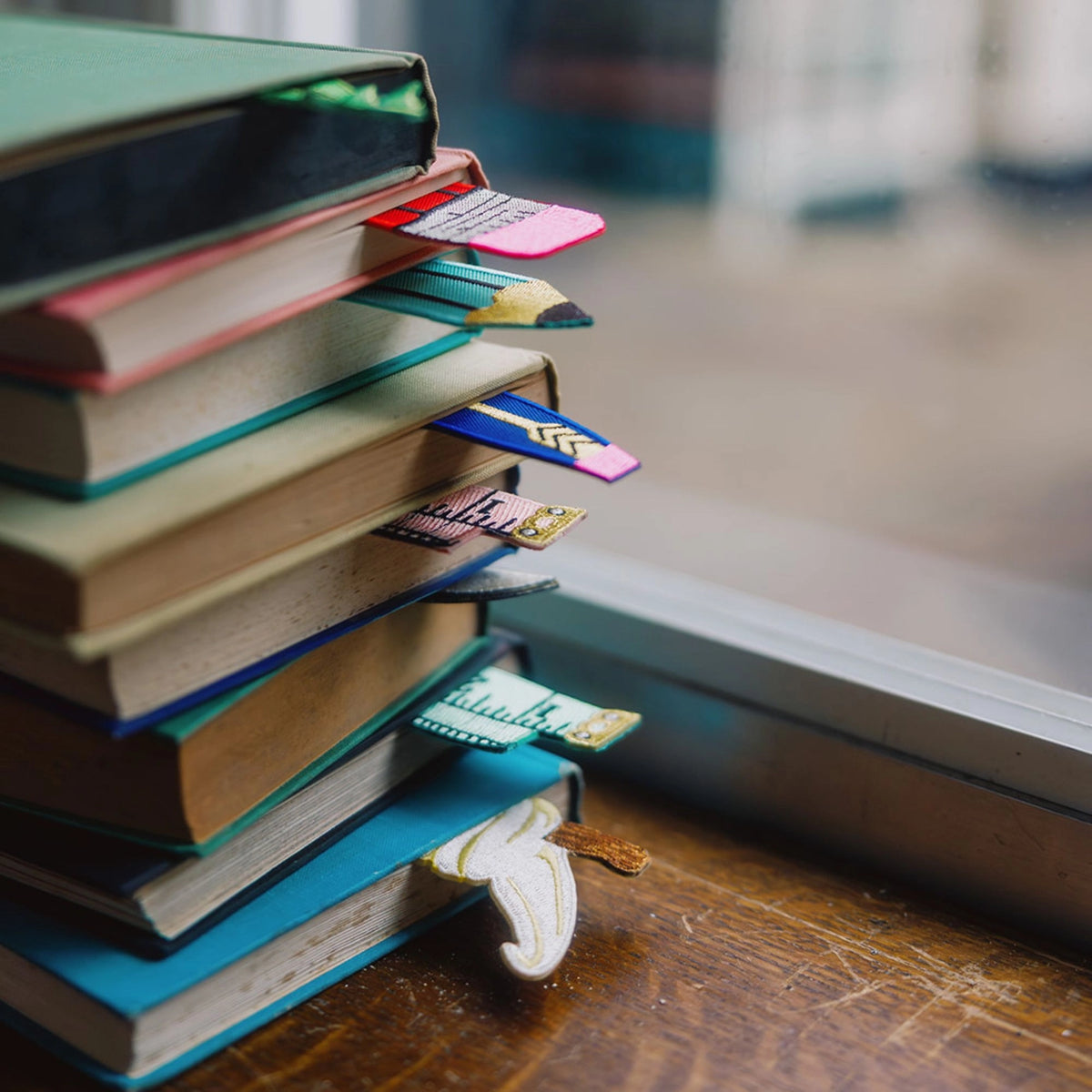 Stack of books with colorful bookmarks on a wooden surface