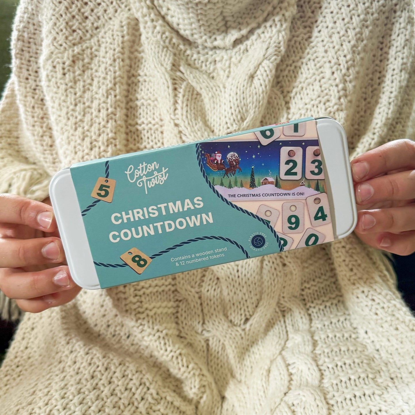 Person holding a phone with a Christmas countdown app on a beige sweater background