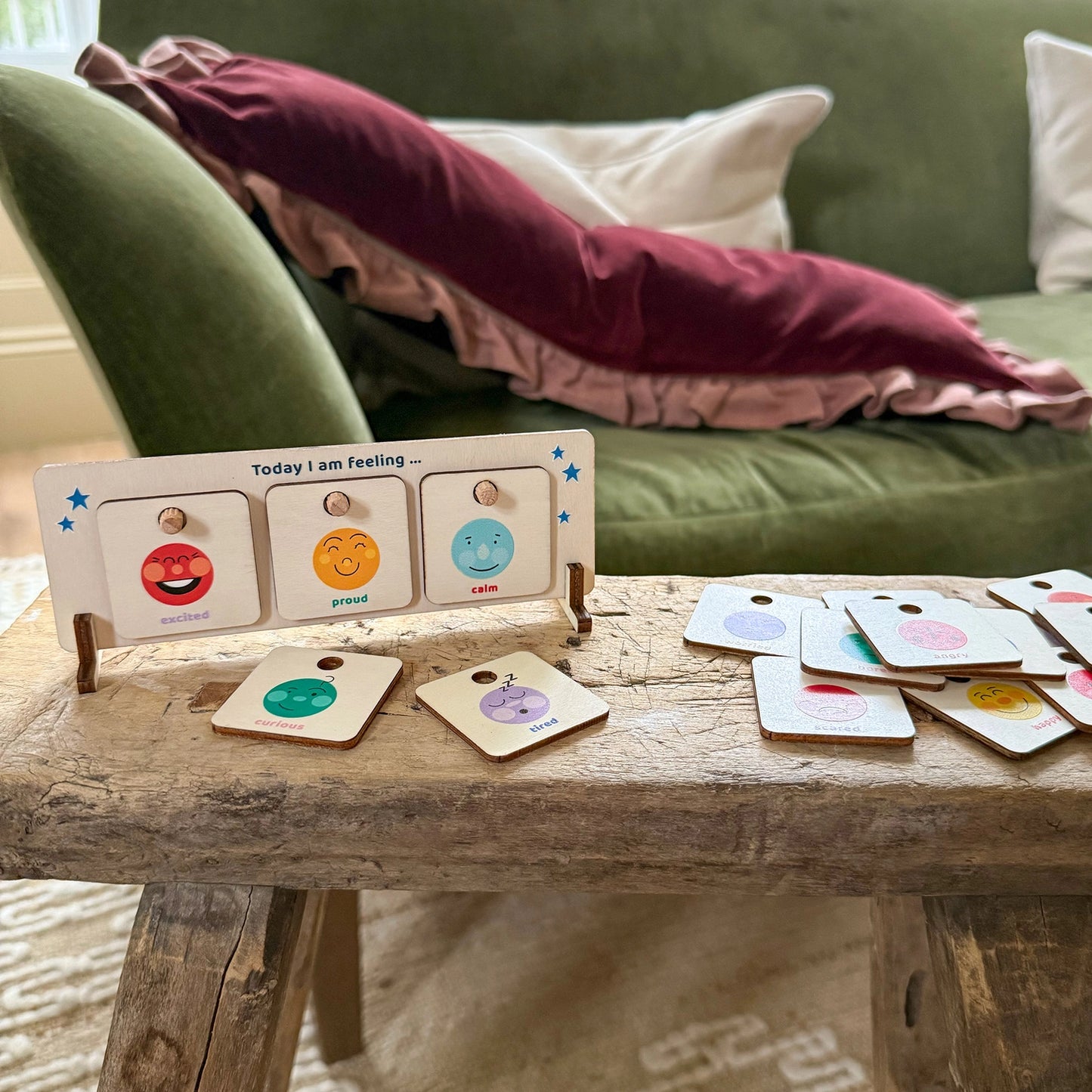 Wooden feelings chart stood on a woodn table, with emotion cards scattered around.