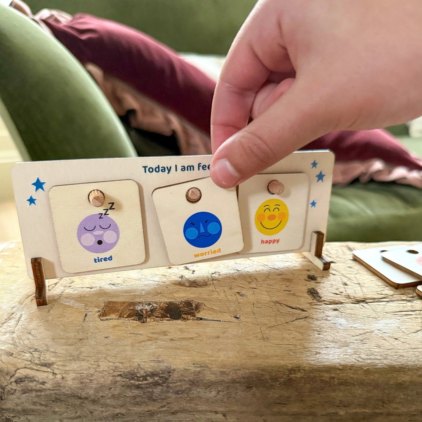 Wooden feelings chart stand, with a hand placing emotion cards onto the display.