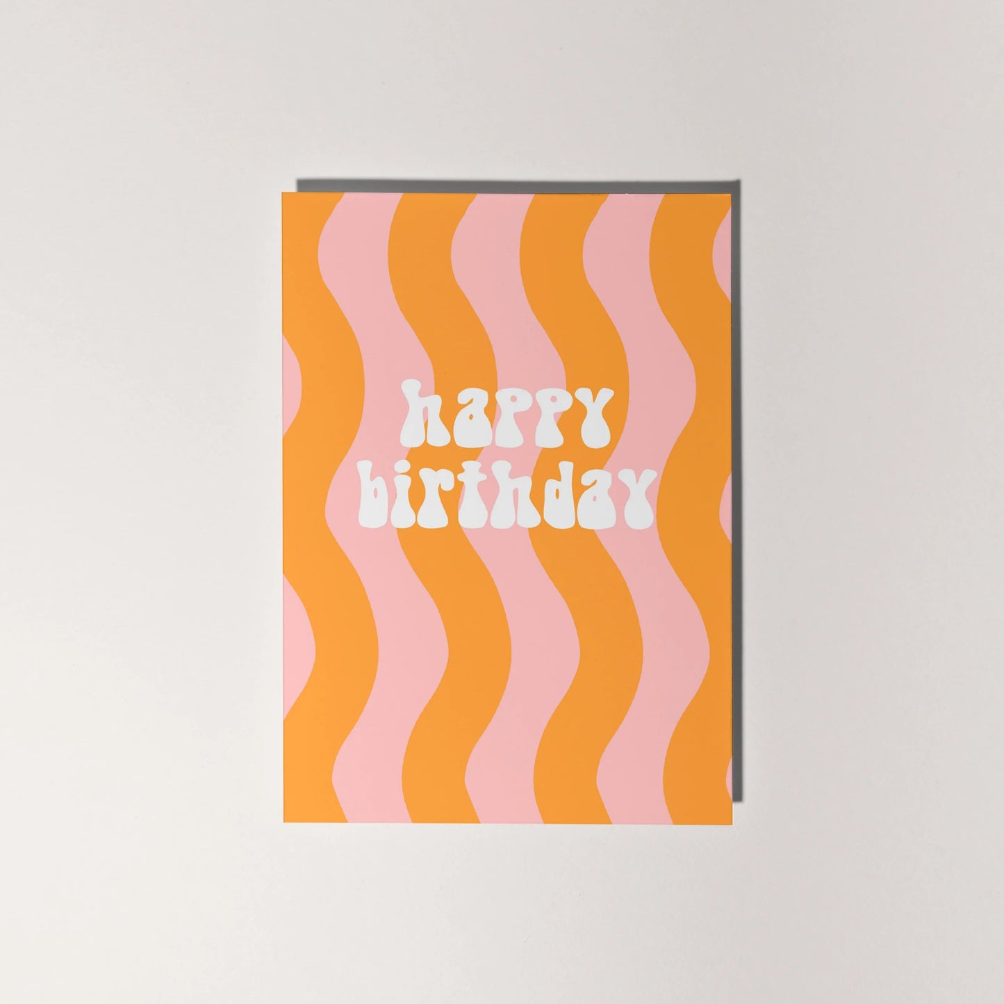 Happy birthday card with retro font and orange and pale pink wavy lines.