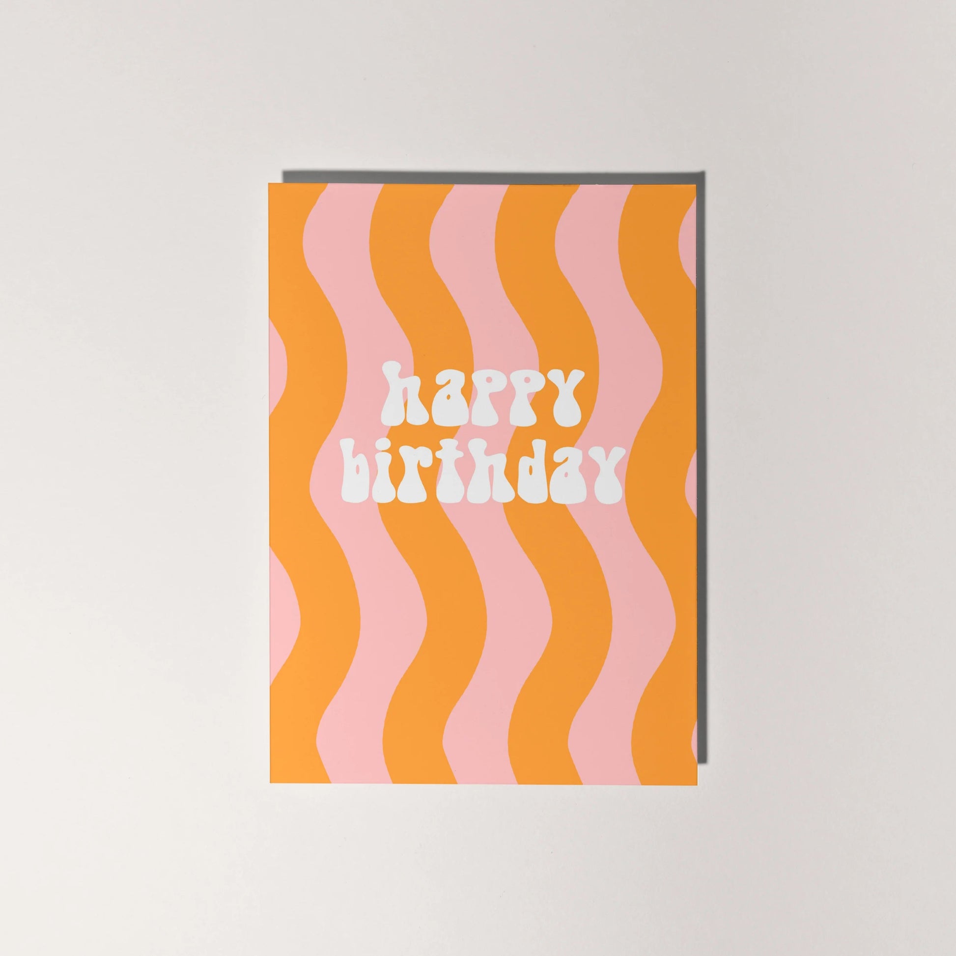 Happy birthday card with retro font and orange and pale pink wavy lines.
