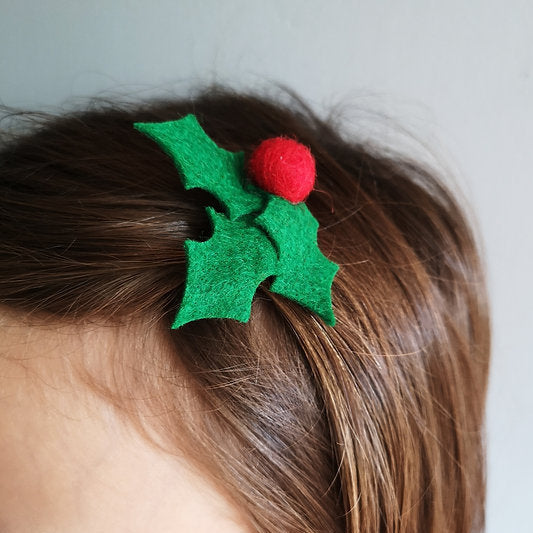 Holly leaf hair clip on a child's head against a plain background