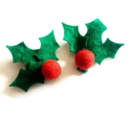Two hair clips in a green holly leave with red berry design, on a white background
