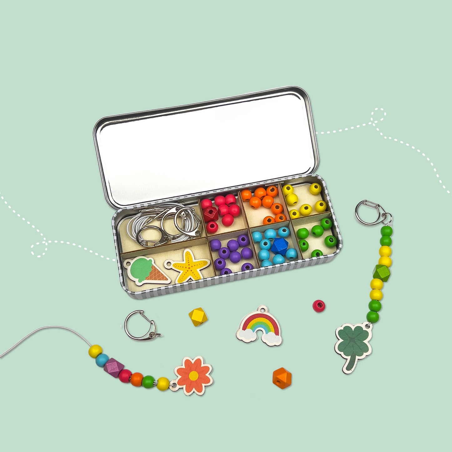 Colorful jewelry-making kit with beads and charms on a light green background