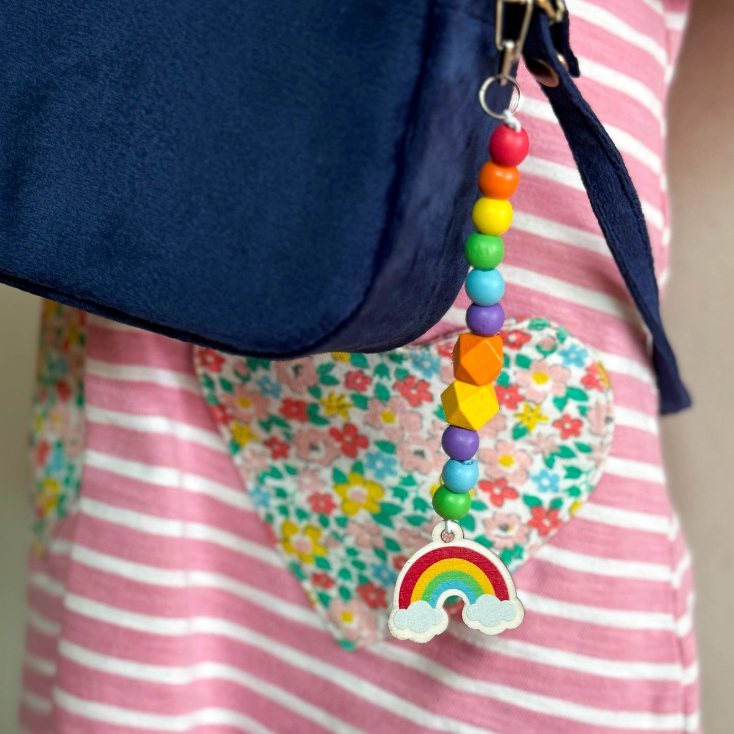 Colorful beaded keychain with a rainbow charm attached to a blue bag.