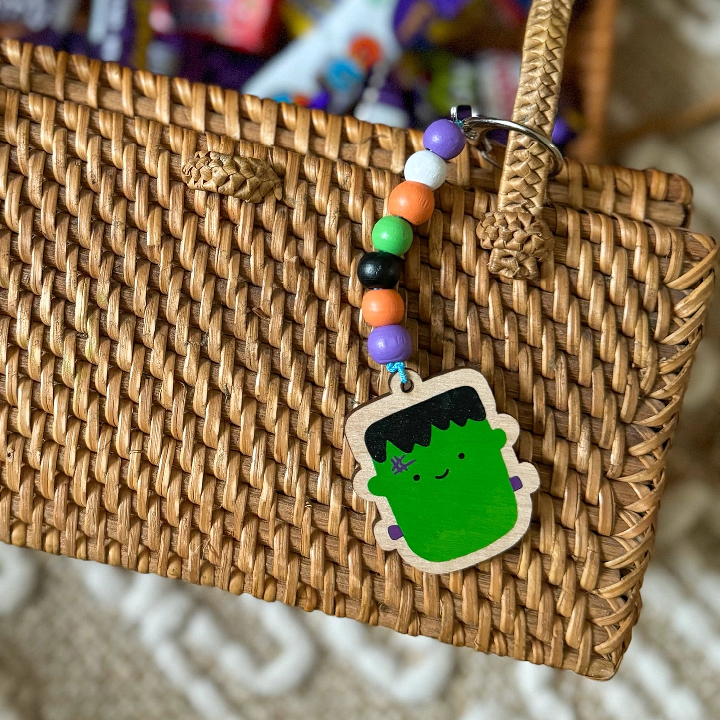 Woven bag with a colorful keychain featuring a monster character on a blurred background