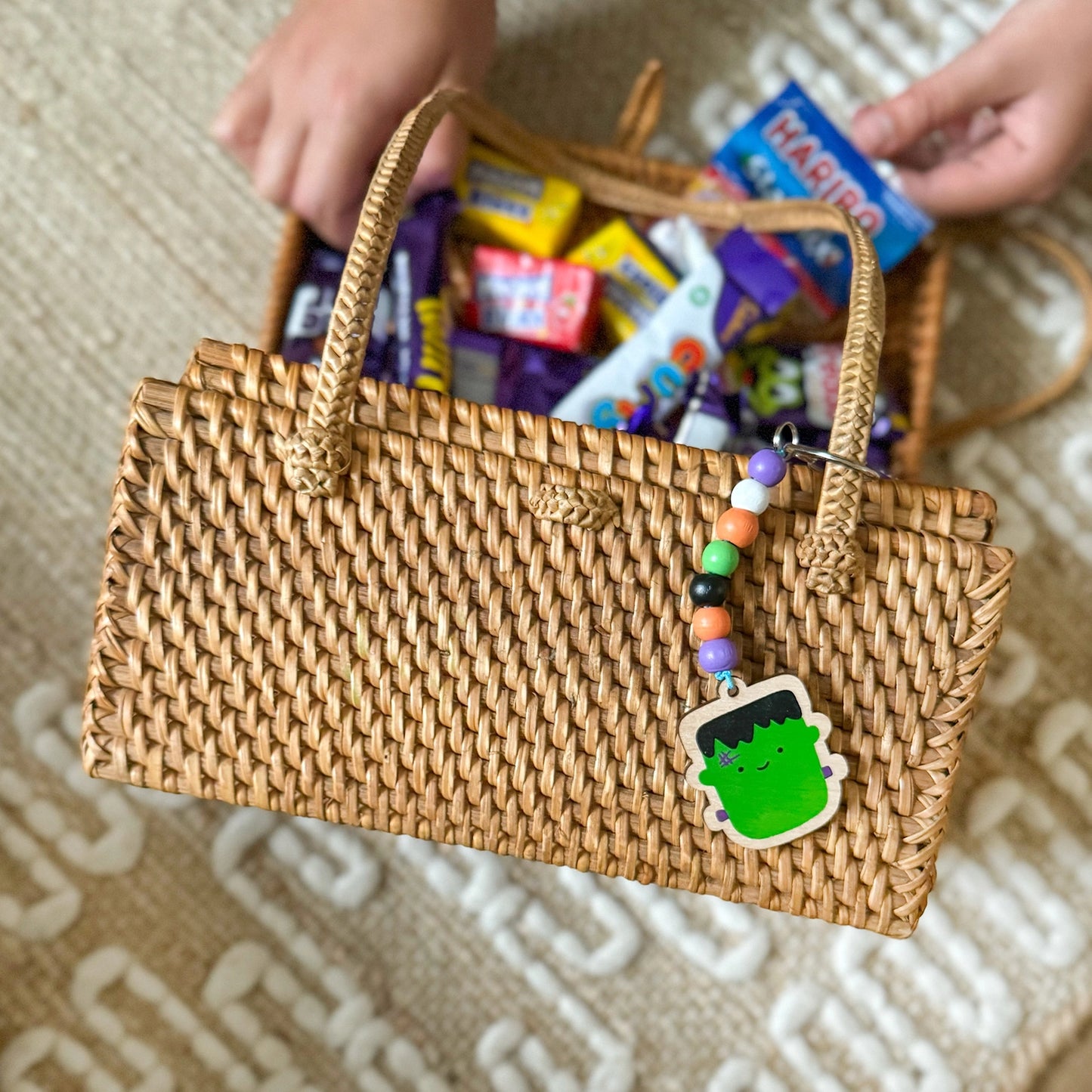 Woven handbag filled with colourful candy on a patterned surface