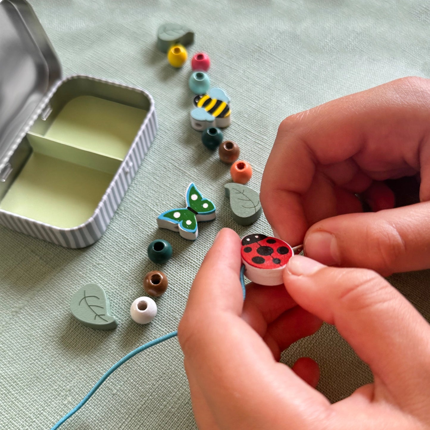 Person assembling colorful miniatures on a textured surface with a small container.