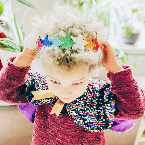 Child wearing a colorful headband with star decorations indoors.