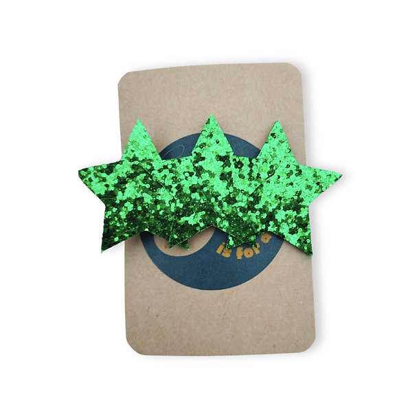 Brown backing card holding a sparkly green hairclip in the shape of 3 stars.