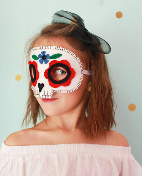 Person wearing a colorful eye mask with floral designs against a light blue background