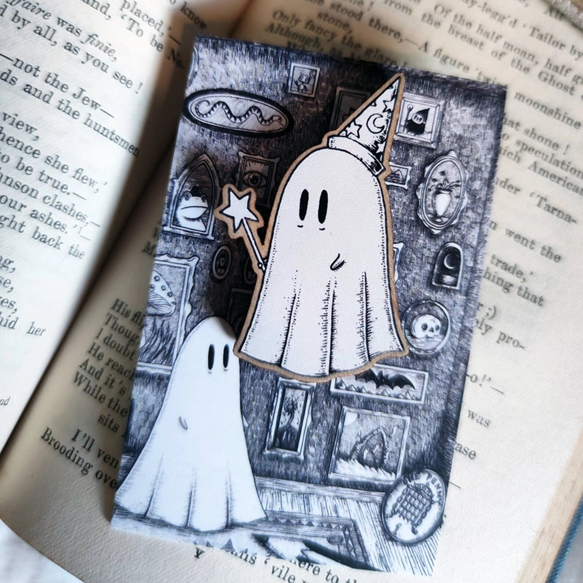 Ghost-themed wizard brooch on an open book with vintage design elements.