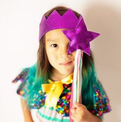 Little girl wearing a purple crown and holding a purple wand.