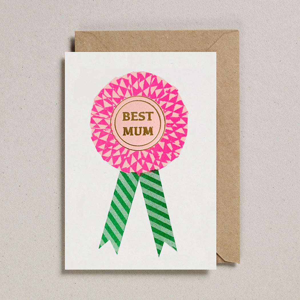 Card with a pink ribbon rosette saying 'Best Mum' on a beige background.