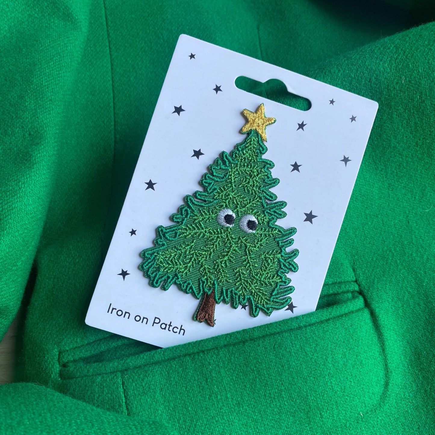 Green Christmas tree iron on patch tucked into the pocket of a green jacket