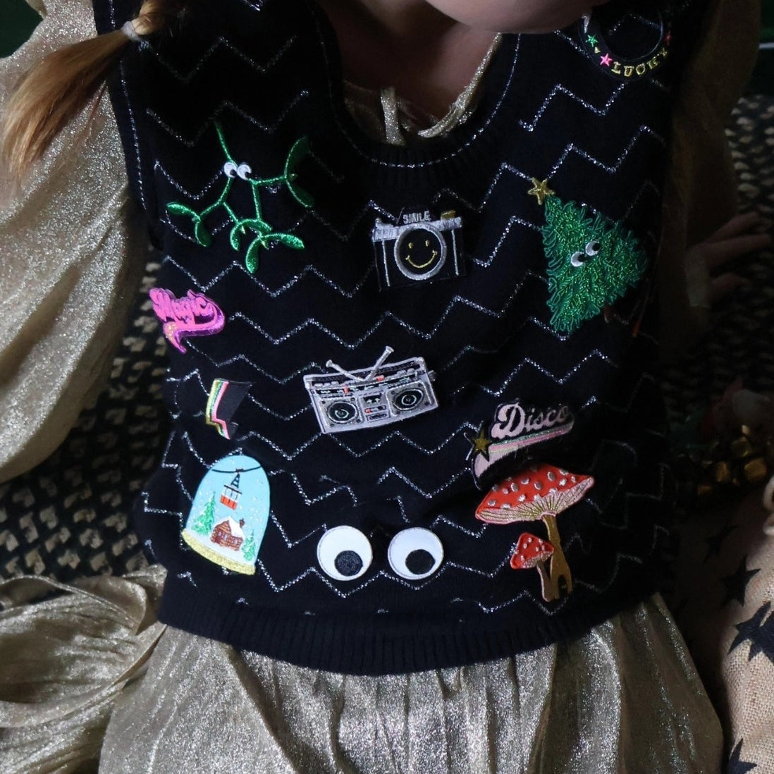 Model wearing sweater vest with several iron on patches, including the Christmas Tree