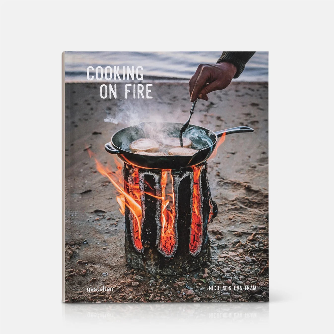 Book cover of 'Cooking on Fire' showing a person cooking over an open flame.