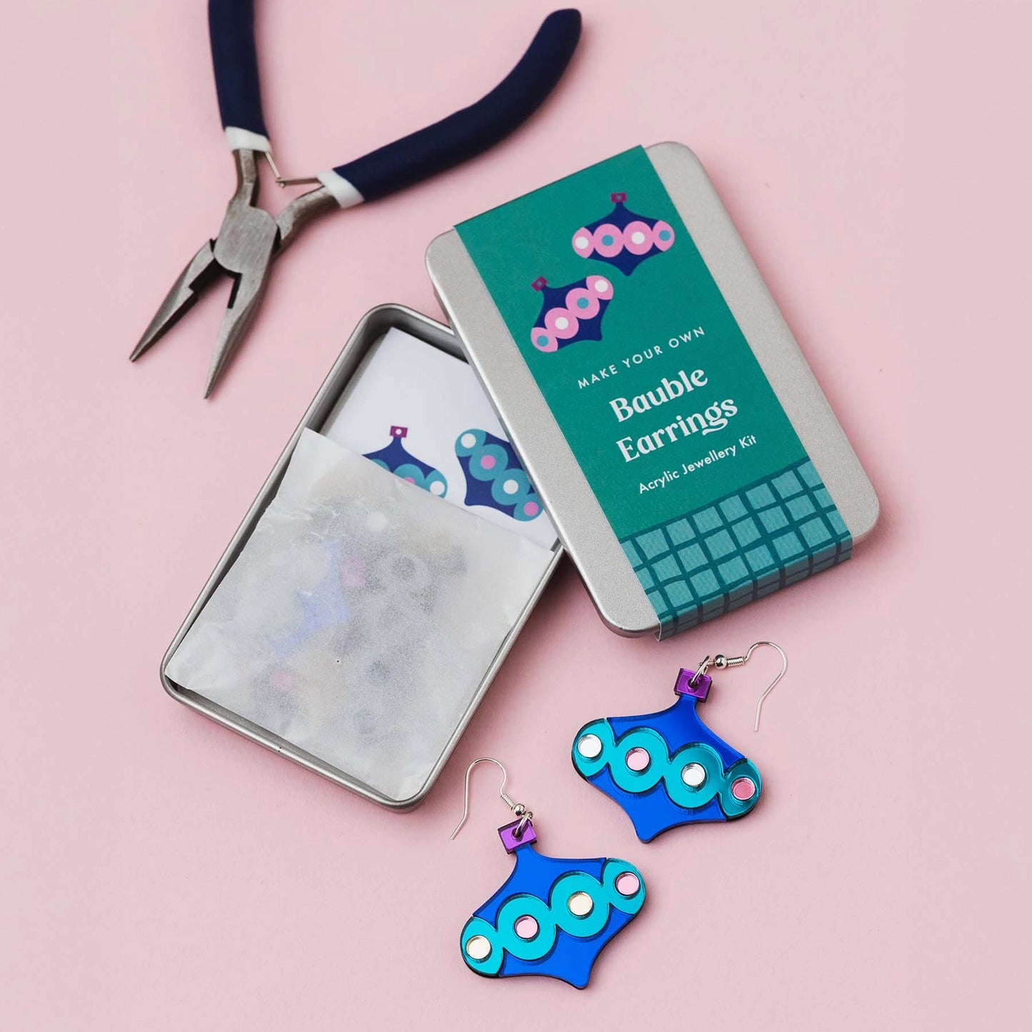 Metal tin lay open, labelled 'Make Your Own' Bauble Earrings, with completed blue and turquoise bauble earrings. 
