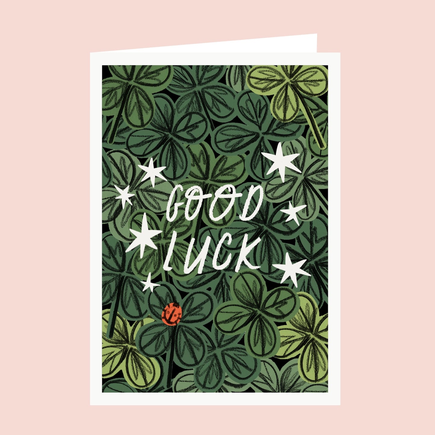 Greeting card with 'Good Luck' text surrounded by green clover and stars on a pink background