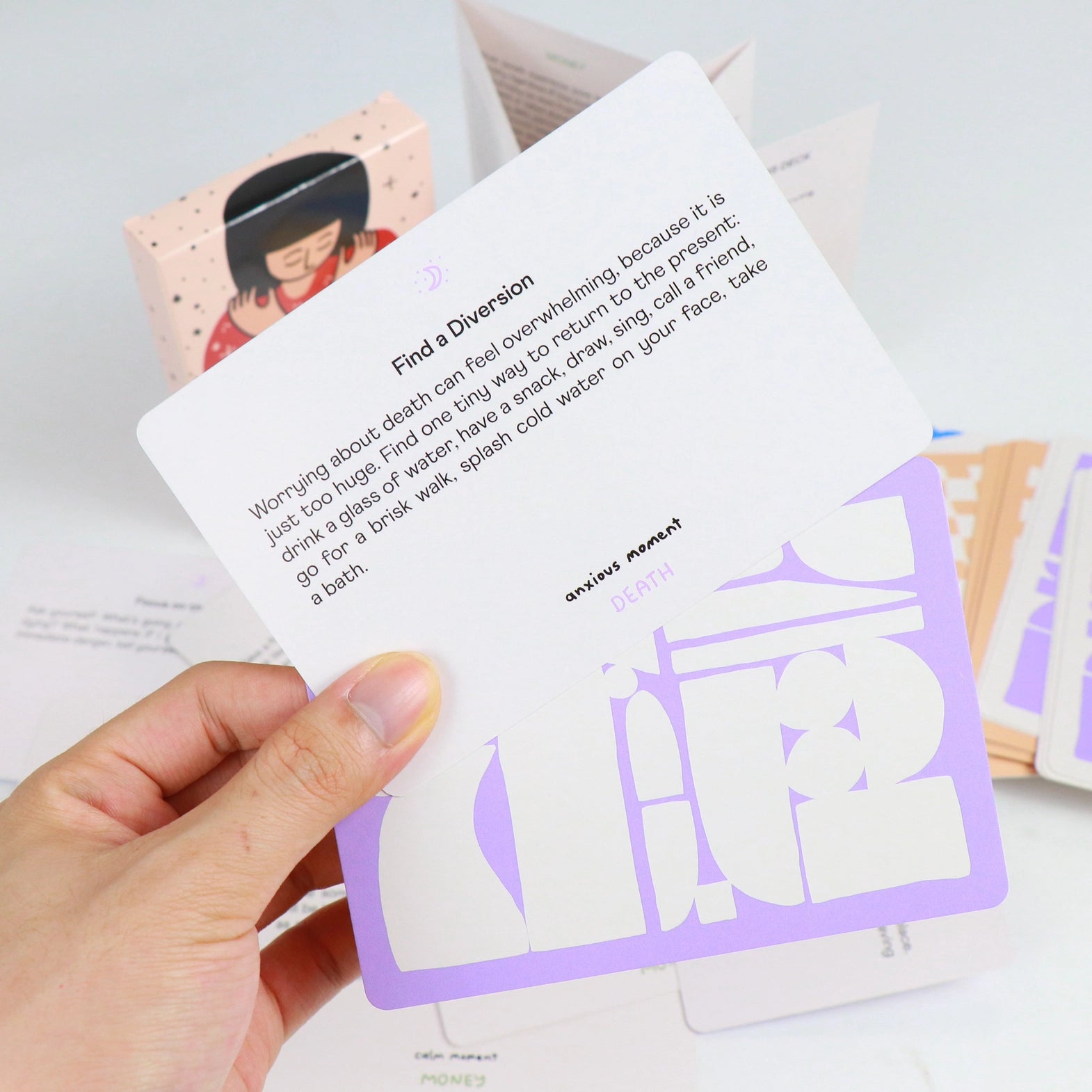 Hand holding a card with text communicating ways to help regulate, and a graphic design on a light background.
