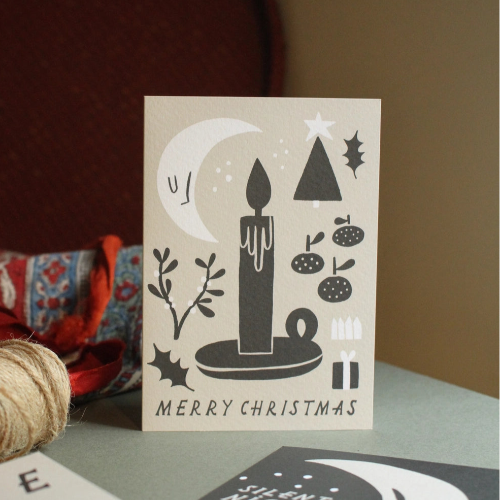 Christmas card with black and white design on a table with other cards.
