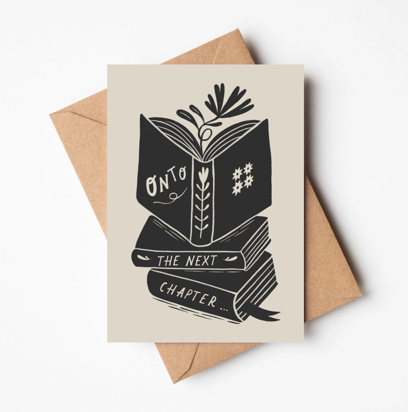 Greeting card with 'Onto the Next Chapter'  book stack design on a beige background with a brown envelope.