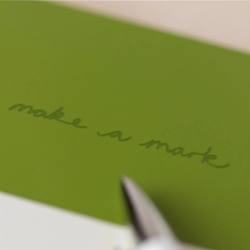 Green paper with 'make a mark' text and a pen tip at the bottom.