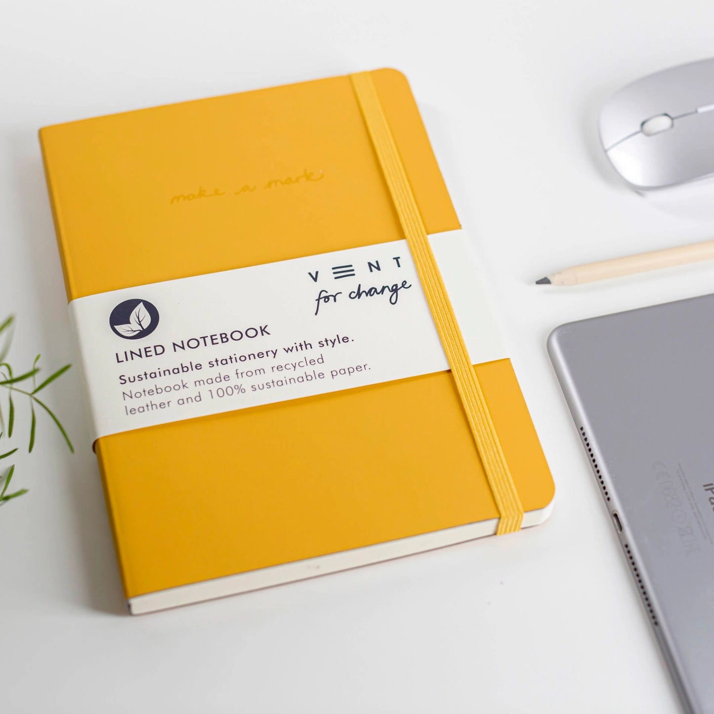 Yellow notebook with a label on a white surface with office items.