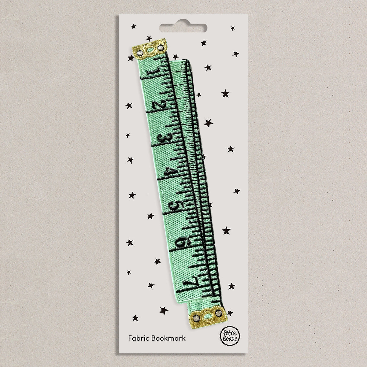 Mint colour, tape measure design embroidered bookmark on a white backing card with black stars.