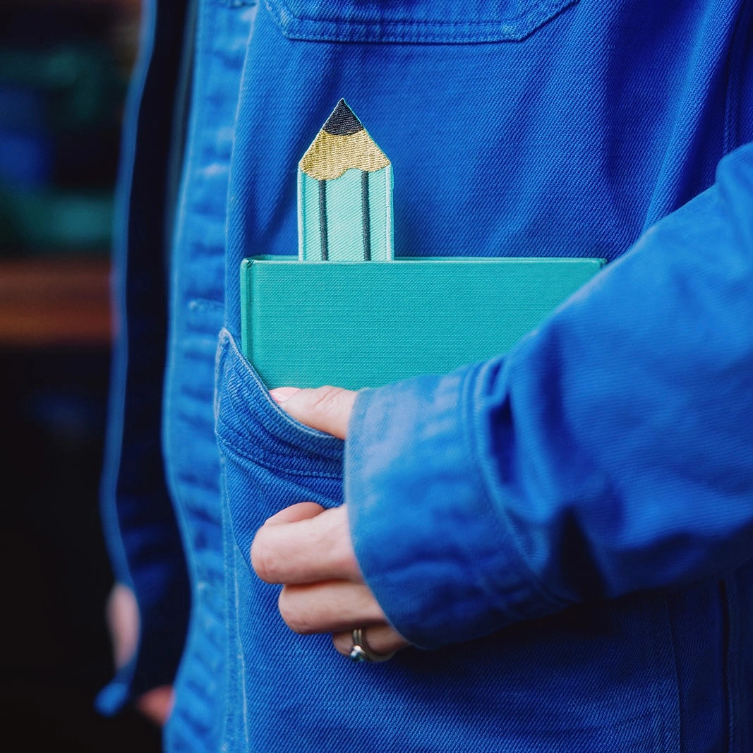 Person in blue jacket with a book in his pocket, marked with a turquoise pencil bookmark.