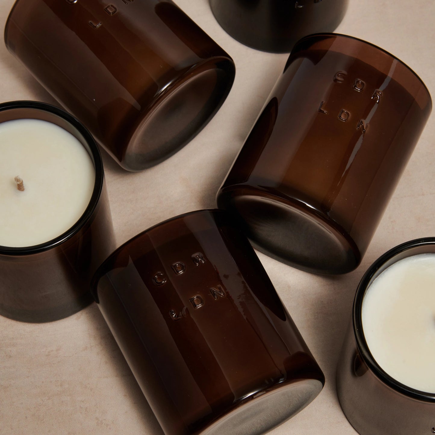 Brown glass candles on a beige surface