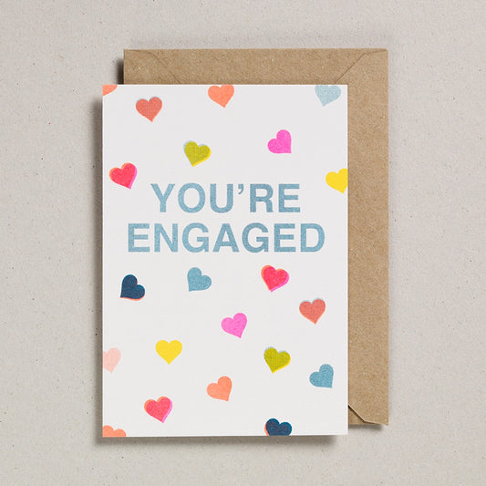 Card with 'You're Engaged' text and colorful hearts on a beige background